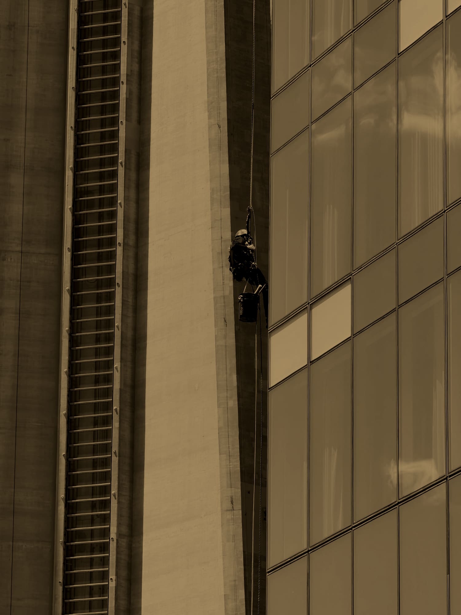 Rope-access technician in a hard hat working a Toronto high-rise facade